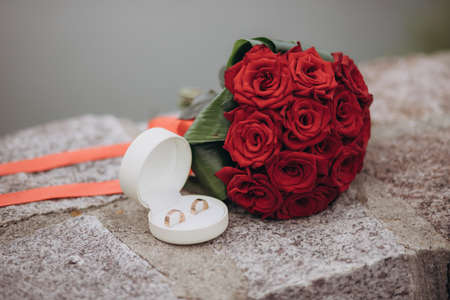 wedding rings lie on a beautiful box near bridal bouquetの写真素材