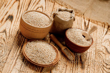 Barley groats in bowls and bags on a wooden background. High quality photo