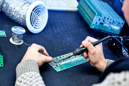 Engineer factory worker electronics solder a board (chip). Microchip Production, Nano computer Technology and manufacturing technological processの写真素材