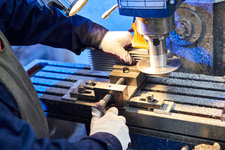 Process engineer working on cutting aluminium billet with machine.  Circular milling machine...
