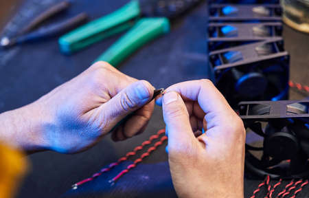 A master technologist makes fans for a computer cooling system. Computer Fan Parts lie on the tableの写真素材