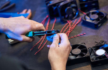 A master technologist makes fans for a computer cooling system. Computer Fan Parts lie on the tableの写真素材