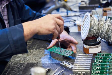 Repairing Hardware Equipment. Repair Shop and Worker with Tools.  Microchip and Circuit Board. Testing Modern Digital Device on Desk . Electronic Devices Concept.の写真素材