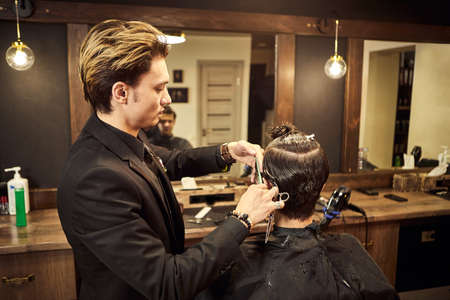 Salon. Man in a barber chair. The hairdresser serves the client in the barbershop. The concept of male cosmetology.の写真素材