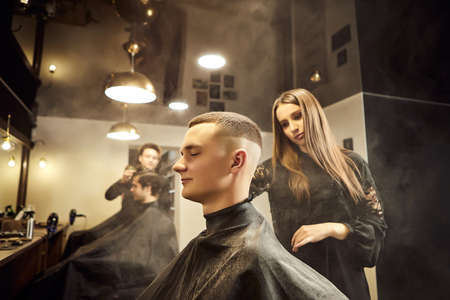 Salon. Man in a barber chair. The hairdresser serves the client in the barbershop. The concept of male cosmetology.の写真素材