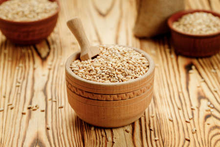 Barley groats in bowls and bags on a wooden background. High quality photoの写真素材