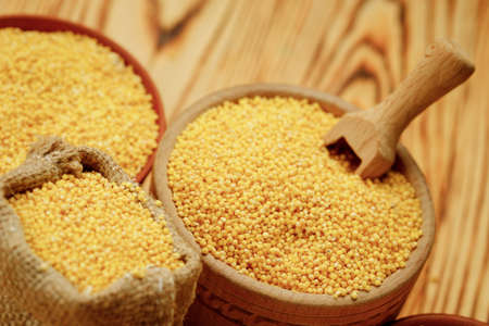 Millet polished in bowls and bags on a wooden background. High quality photoの写真素材