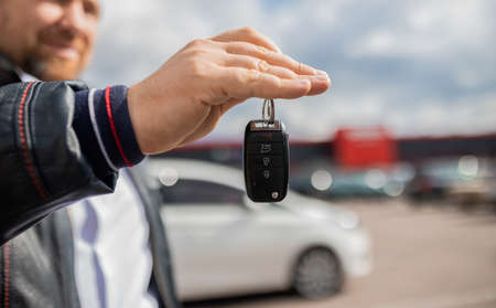 Ð¡lose up. Hand giving a car key. Concept of successful car transaction sale-purchase deal