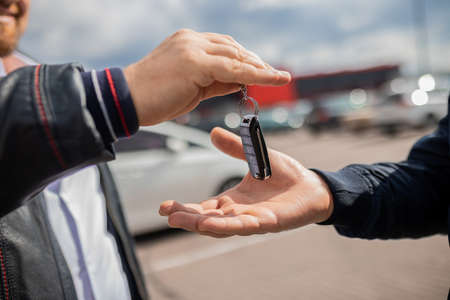 Ð¡lose up. Hand giving a car key. Concept of successful car transaction sale-purchase deal