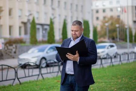 Young happy businessman working with documents near business centre