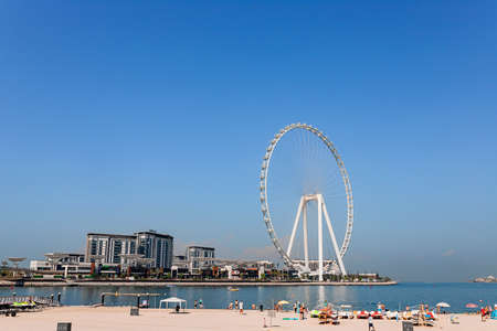 Dubai, UAE, November 2021, Panoramic view from JBR Beach over water towards Bluewaters Island with the Ain Dubai, the tallest and biggest observation or Ferris wheel in the world; people on beachのeditorial素材