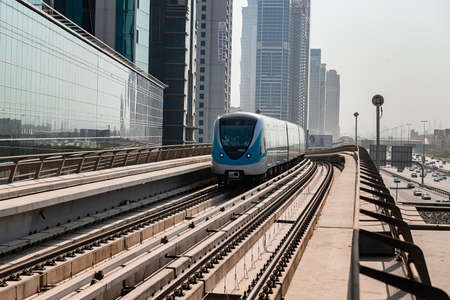 Dubai, United Arab Emirates - November 08, 2021: Dubai metro train on rails at background of skyscrapers. Famous outdoor subway Red Lineのeditorial素材