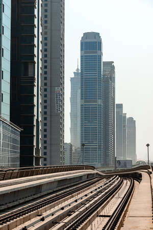Dubai, United Arab Emirates - November 08, 2021: Dubai metro train on rails at background of skyscrapers. Famous outdoor subway Red Lineのeditorial素材