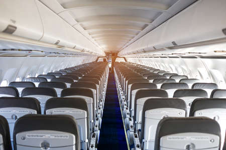 Passenger plane interior. Empty airplane interior with chairs and folding tables in seat back. Cabin...