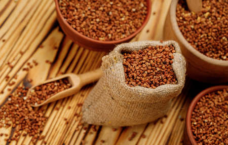 Buckwheat groats in bowls and bags on a wooden background. High quality photoの写真素材