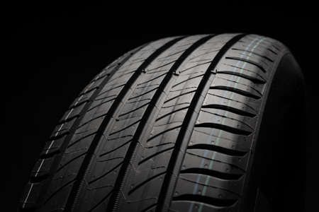 New car tire. Road wheel on dark background. Summer Tire with asymmetric tread design. Driving car...