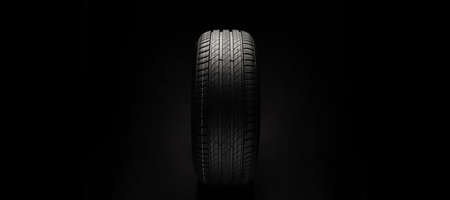 New car tire. Road wheel on dark background. Summer Tire with asymmetric tread design. Driving car concept.の写真素材