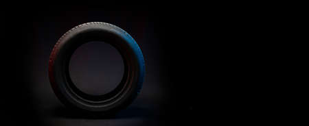 New car tire. Road wheel on dark background. Summer Tire with asymmetric tread design. Driving car concept.の写真素材