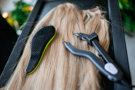 A set of several hair extension tools for a blonde woman in a beauty salon. Pliers and micro tubes.