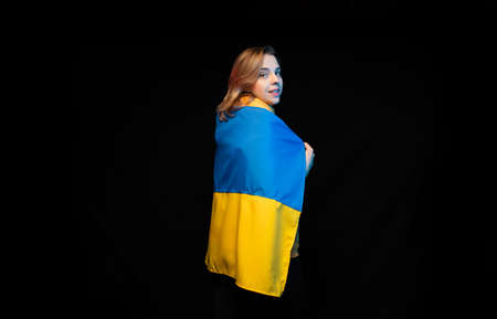 Beautiful Ukrainian girl with the national state flag of Ukraine on black background. Copy space....