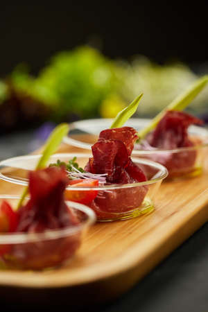 Appetizer from dry cured ham, prosciutto slices on a dark background. Photo for restaurant menu