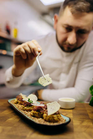 Chief chef serving snacks, canapes or sandviches adding finishing touch on dish before it is going to be served for restaurant guestsの写真素材