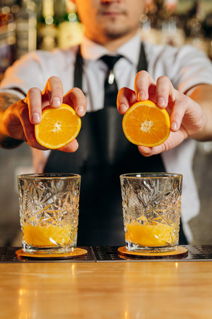 The bartender prepares freshly squeezed orange juice or cocktailの写真素材