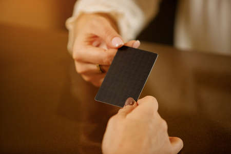 Receptionist girl with visit card in hands. Close up. The hostess at the reception holds a business card of the company or hotel. Place for your logoの写真素材