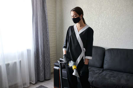 Cleaning service company employee removing dirt from furniture in flat with professional equipment. Female housekeeper arm cleaning sofa with washing vacuum cleanerの写真素材