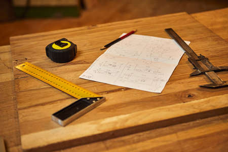 Carpenter's pencil, tape measure, square and carpentry drawings on the workshopの写真素材