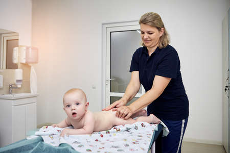 Massage therapist working with cute baby child in medical centerの写真素材
