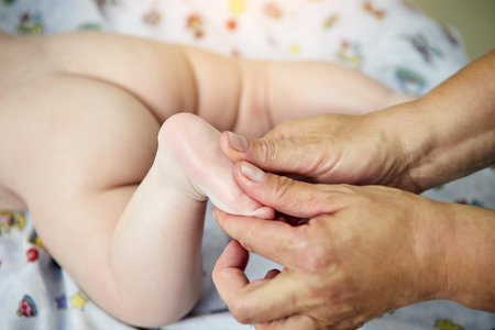Close up of massage therapist working with cute baby child in medical centerの写真素材