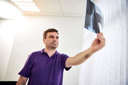 The traumatologist doctor looking at X-ray or mri picture in privat clinic. Physiotherapist or orthopedic in rehabilitation center. Medicine and healthcare conceptの写真素材