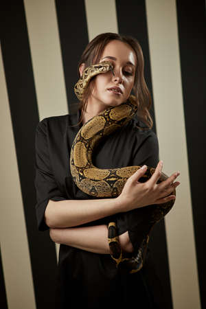 Portrait of beautiful female doctor cosmetologist with snake in the modern clinic. Symbol of...