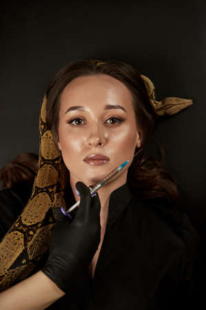 Portrait of beautiful female doctor cosmetologist with snake in the modern clinic. Symbol of...