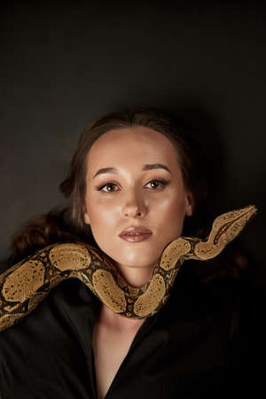 Portrait of beautiful female doctor cosmetologist with snake in the modern clinic. Symbol of...