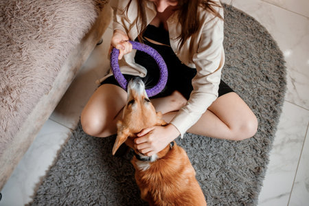 Attractive girl hug and play with corgi dog at home. Welsh Corgi Pembroke with his owner woman on the floor at living roomの写真素材