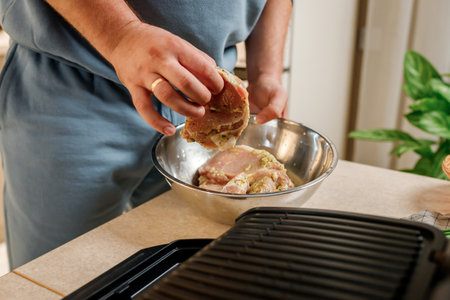 The man's hands prepares delicious juicy meat steak on an electric grill on wooden table. Smoke in the home kitchenの写真素材