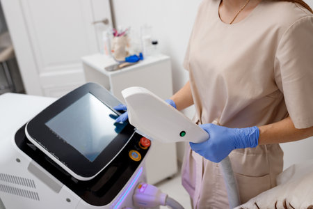 Professional cosmetologist is making cavitation rejuvenation skin treatment in clinic. Radio wave lifting. Beautician hand holding ultrasound device for face lifting procedureの写真素材