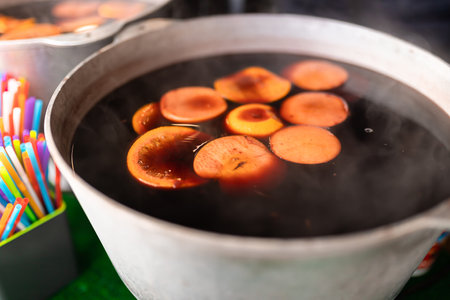Christmas mulled wine at the fair brewed in a cauldron with cinnamon and citrus. Cooking a traditional Christmas and New Year's drinkの写真素材