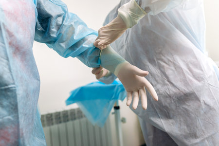 Close up of nurse putting on medical gloves on surgeon before the operation. Doctors prepare for surgery in the operating room, put on a medical uniformの写真素材