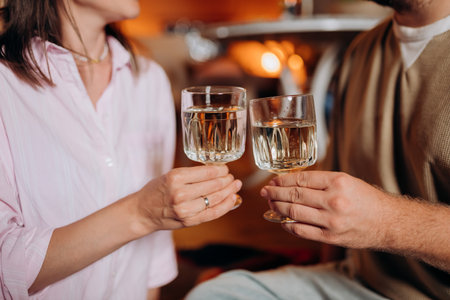 Happy couple relaxing in glamping on summer evening and drinking wine near cozy bonfire. Luxury camping tent for outdoor recreation and recreation. Lifestyle conceptの写真素材