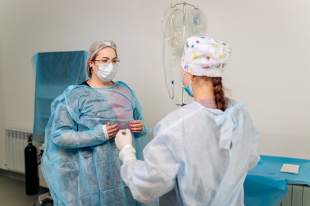 Nurse ties a sterile gown to the surgeon before the operation. Doctors prepare for surgery in the operating room, put on a medical uniformの写真素材