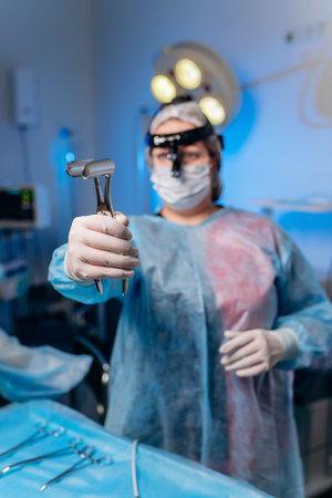 A female surgeon in the operating room holds an anus dilator. A doctor in a medical mask prepares medical instruments for coloproctological surgeryの写真素材