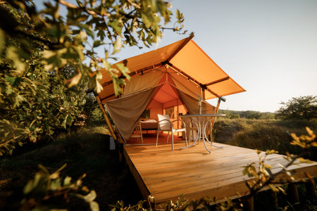 Cozy open glamping tent with light inside during sunset. Luxury camping tent for outdoor summer holiday and vacation. Lifestyle conceptの写真素材