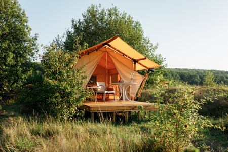 Cozy open glamping tent with light inside during sunset. Luxury camping tent for outdoor summer holiday and vacation. Lifestyle conceptの写真素材