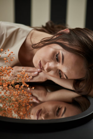 Portrait of smiling woman cosmetologist with flowers. Female beautician at her workplace in cosmetology clinicの写真素材