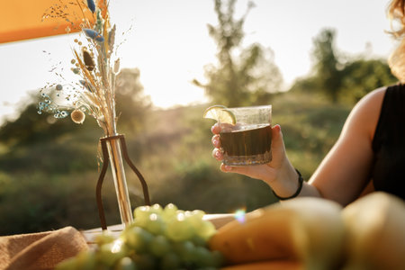 Happy Woman freelancer use phone and drinking cocktail call while relaxing on cozy glamping tent in sunny day. Luxury camping tent for outdoor summer holiday and vacation. Lifestyle conceptの写真素材