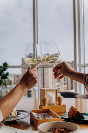Close up of hands toasting wine glasses at dinner in restaurant. Drinks and celebration conceptの写真素材