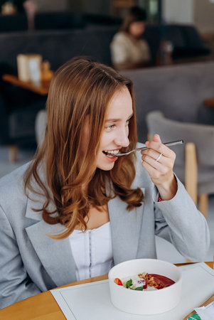 Young attractive woman enjoys tasty meal on cafe or restaurant backgroundの写真素材